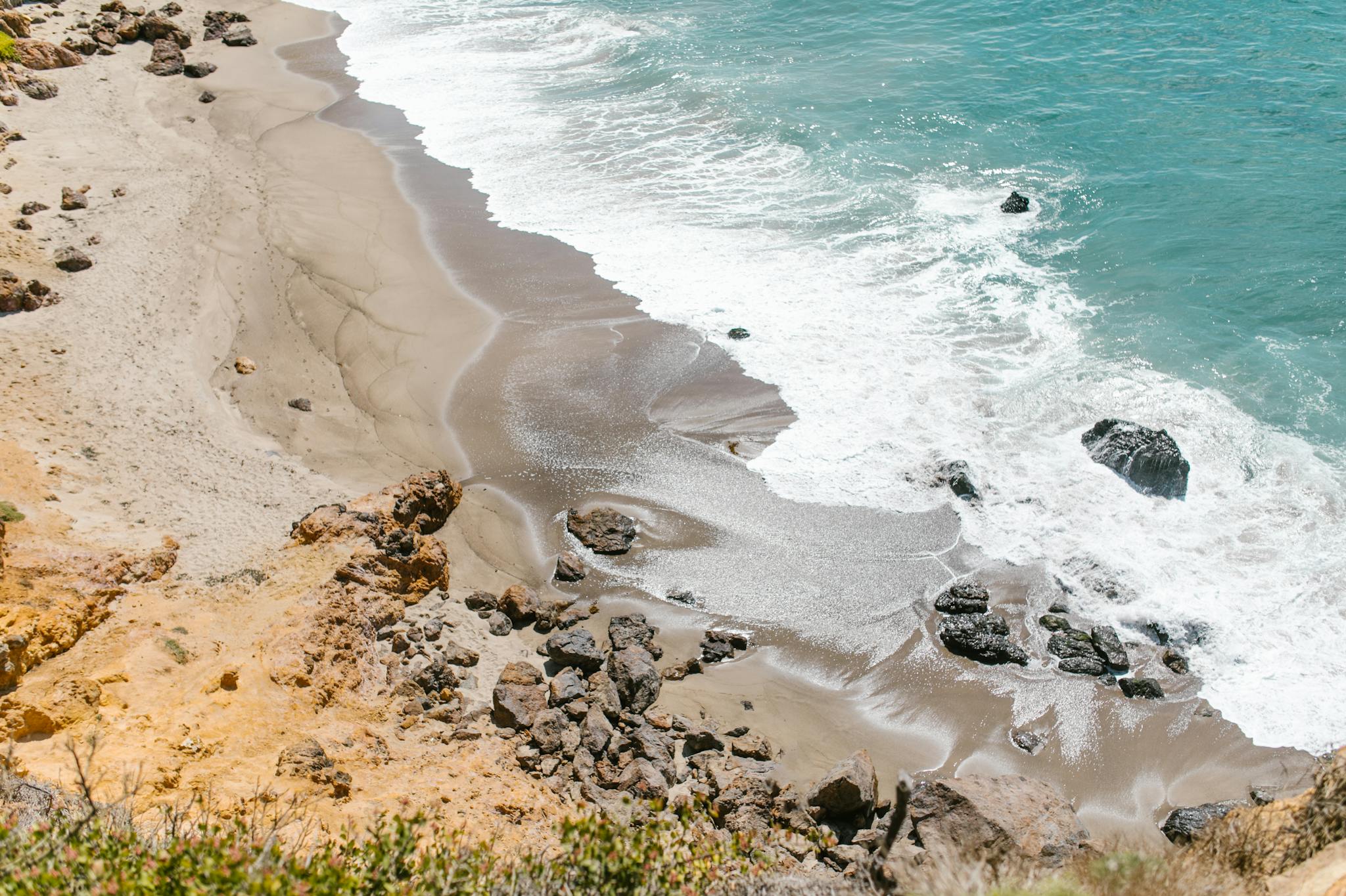 Aerial view of a rocky shoreline meeting the ocean waves.