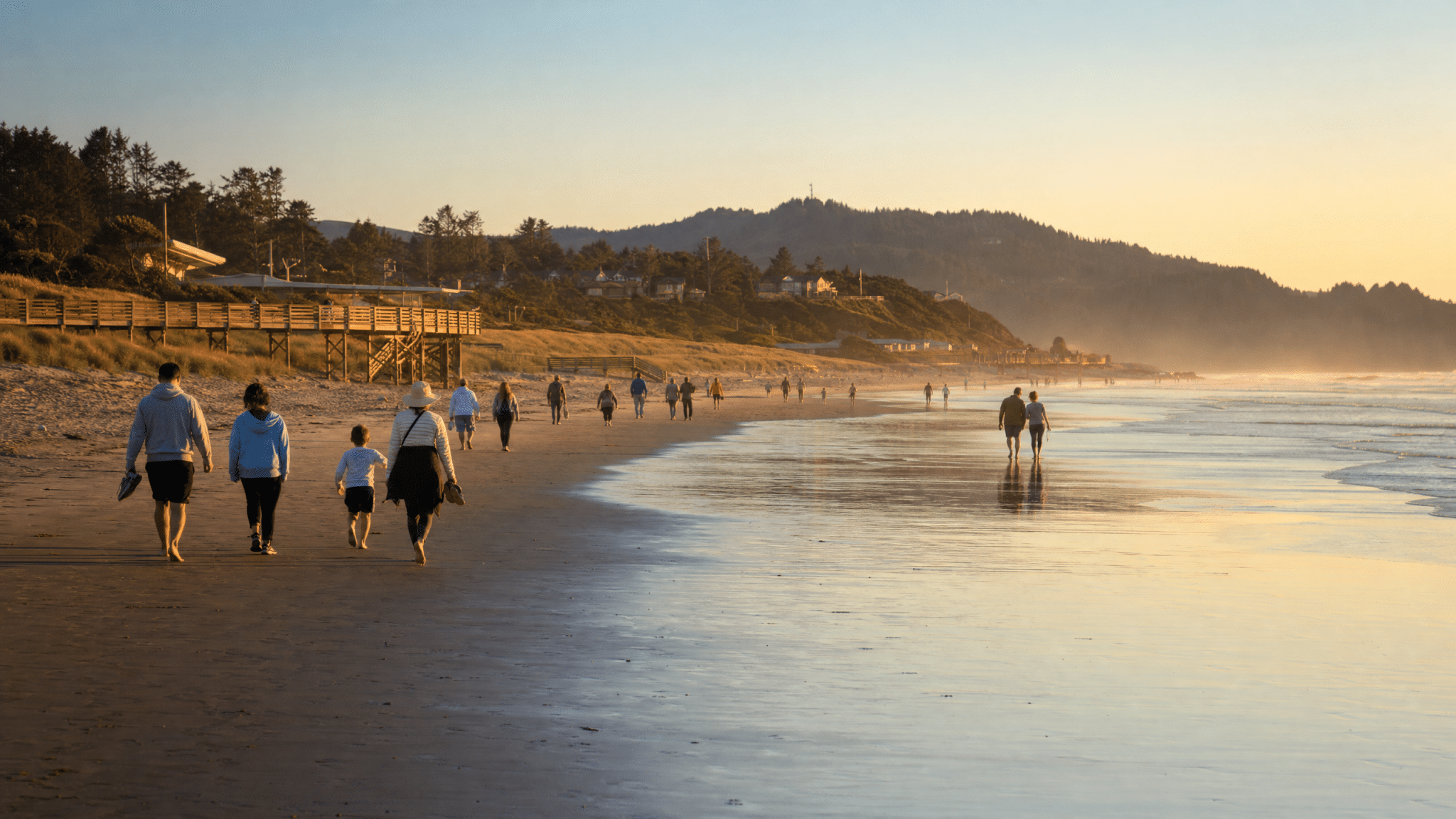 Families enjoying a wide sandy beach at sunset on the Oregon Coast