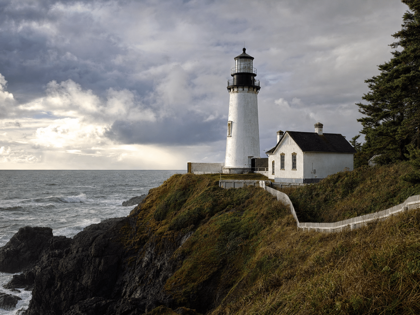 Historic lighthouse on rocky Oregon Coast headland with dramatic sky