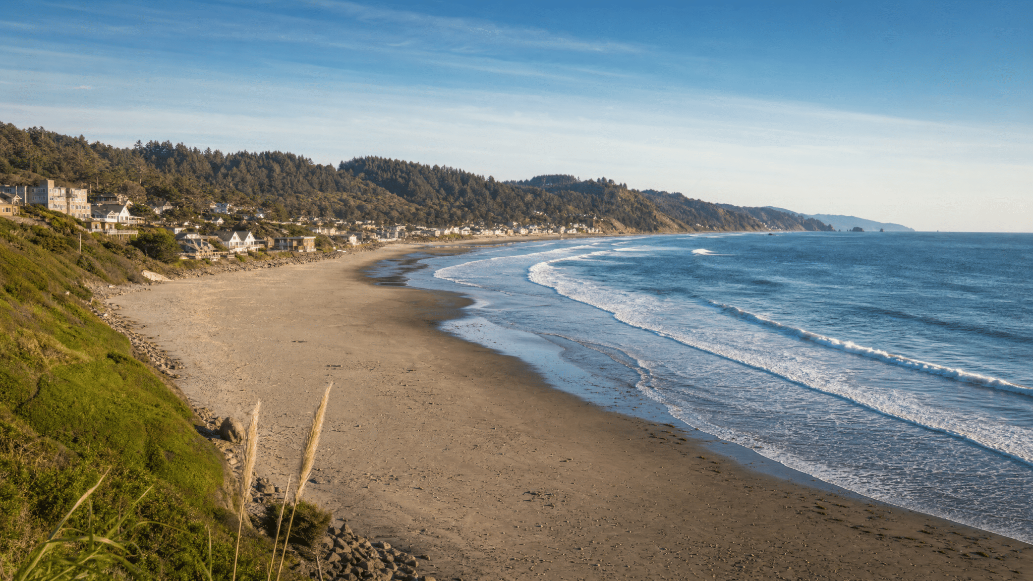 Lincoln City beach with coastal town and forested backdrop