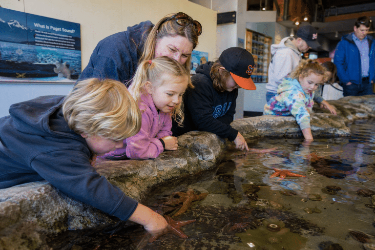 Families walking toward the entrance of the Oregon Coast Aquarium in Newport, Oregon.