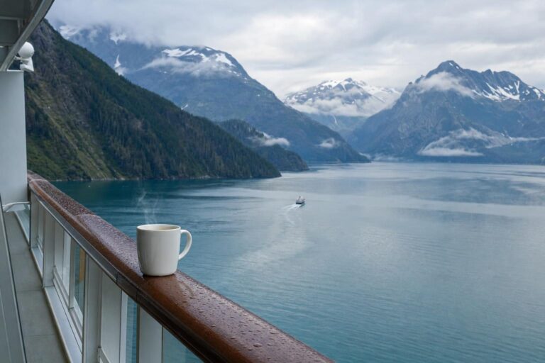 Misty fjord and forested mountains seen from a cruise ship balcony at dawn