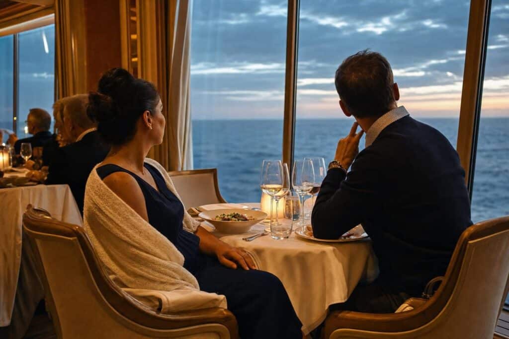 Couple in smart casual dinner outfits at a cruise ship dining table with a cardigan for Alaska evenings