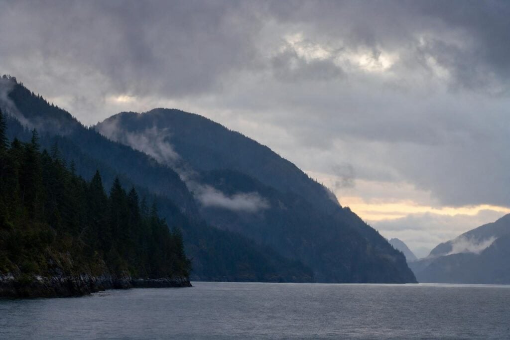 Cloudy overcast evening over a misty Southeast Alaska fjord, the main obstacle to Alaska cruise northern lights