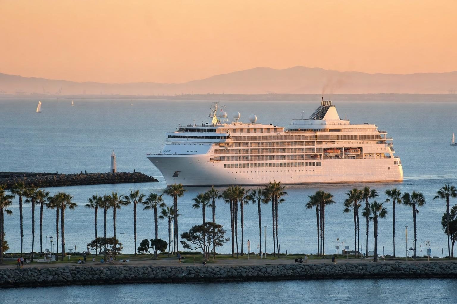 Cruise ship leaving a Southern California harbor at golden hour with palm trees and sailboats