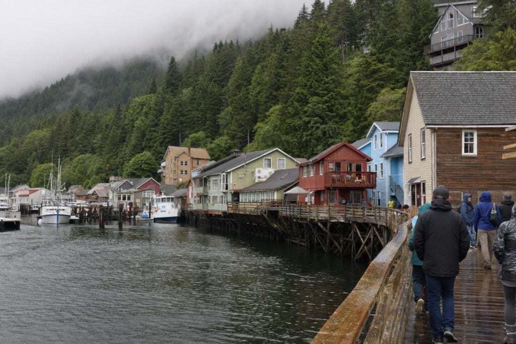 Small waterfront Alaska town with fishing boats and rainforest hillside, a typical Inside Passage cruise port