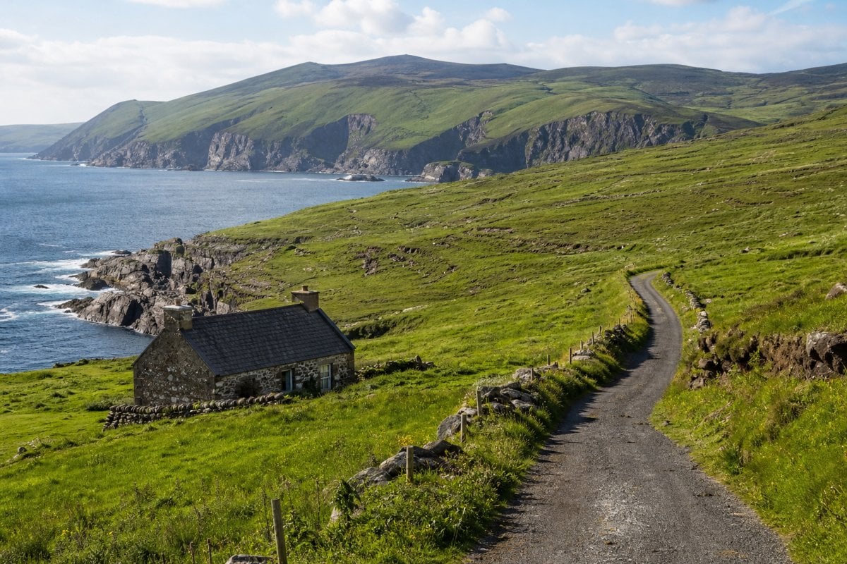 Green coastal hills and a stone cottage in Ireland