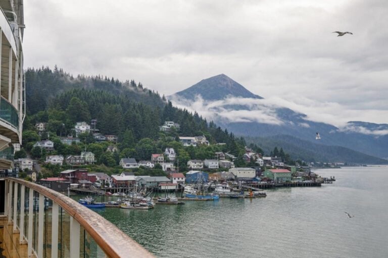 Misty Alaska harbor town and conical mountain seen from a cruise ship deck on a calm overcast morning