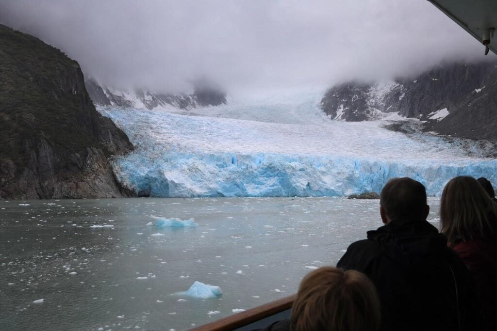 Blue tidewater glacier face and floating ice seen from a cruise ship deck on an Alaska glacier day